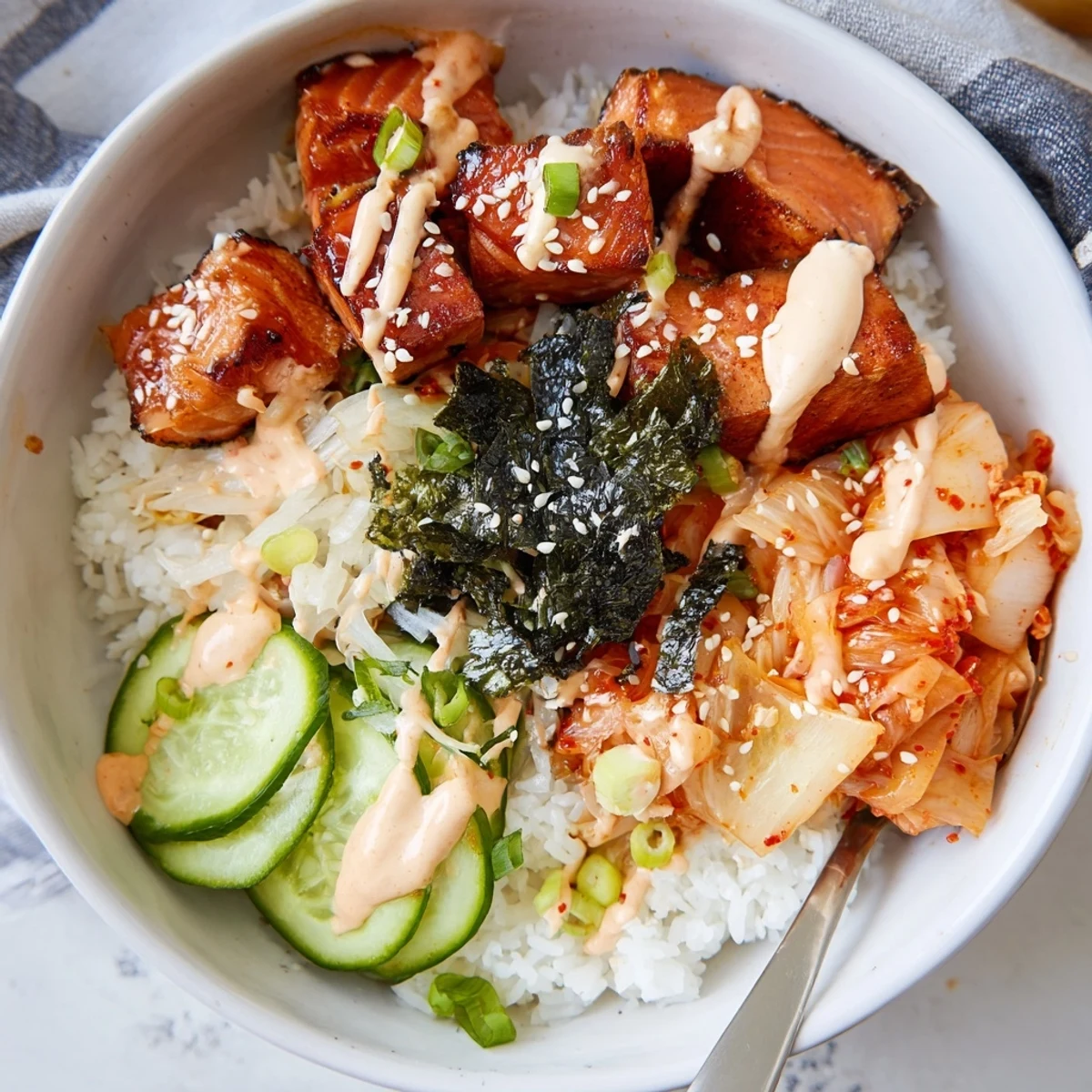 Flavorful crispy salmon rice bowl garnished with crunchy garlic and fresh cucumber.