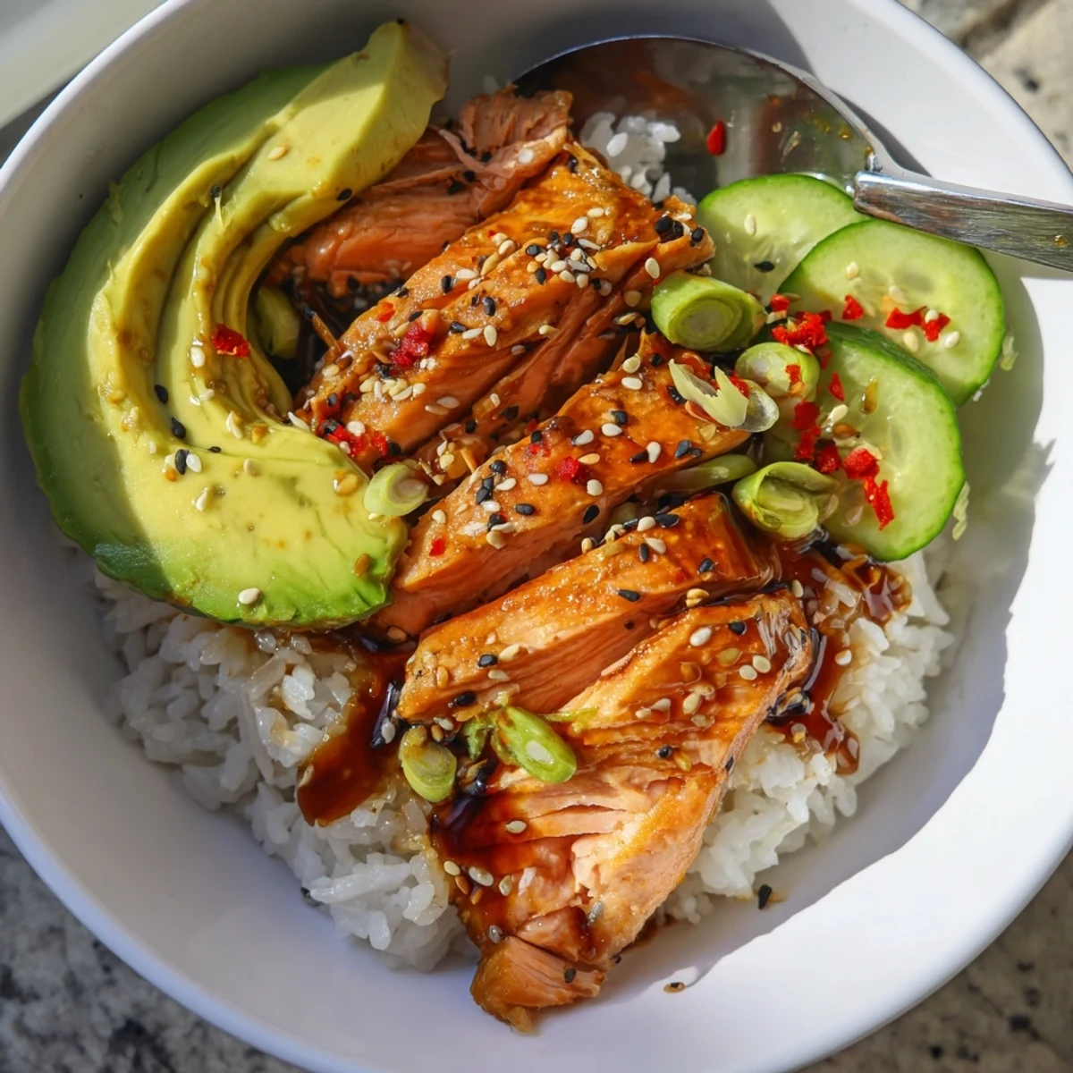 Flaky leftover salmon and rice bowl, garnished with fresh avocado and crunchy cucumber.  