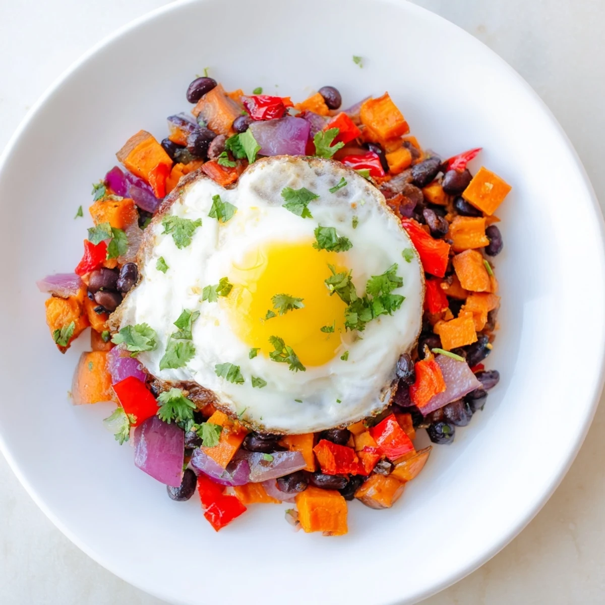 Golden sweet potato & black bean breakfast hash with perfectly fried eggs, ready to eat.