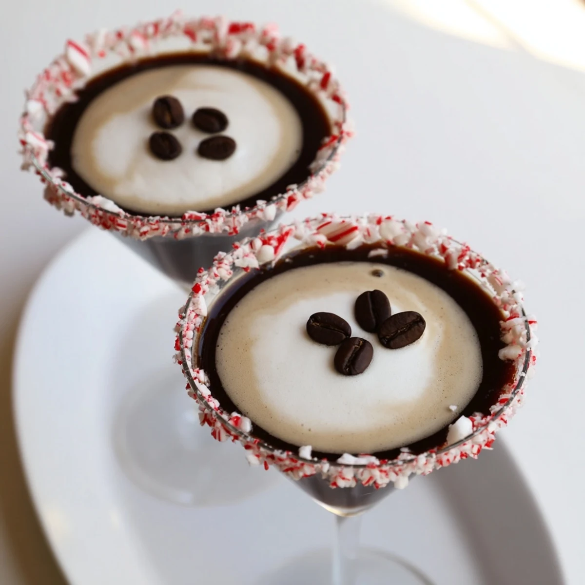 Frothy Peppermint Espresso Martini in a glass, with a chocolate and crushed candy cane rim.