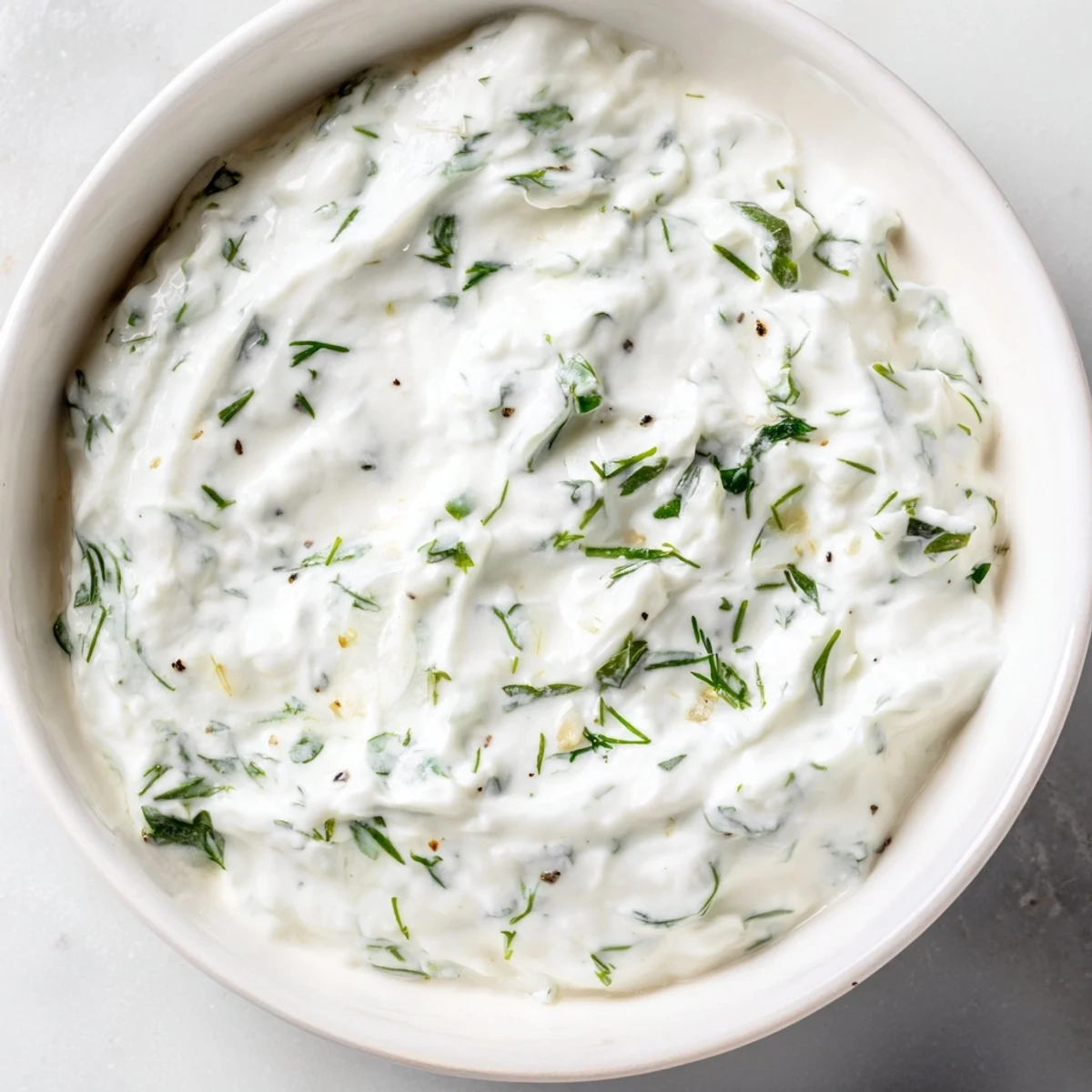 A vibrant bowl of Greek yogurt herb dip, ready to be served with crunchy vegetable sticks.