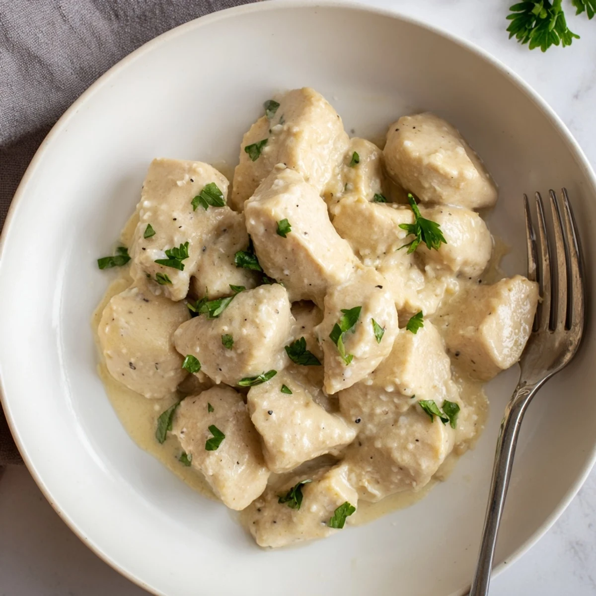 Sizzling skillet of Creamy Garlic Chicken Bites, featuring a luscious parmesan sauce and aromatic herbs, ideal with crusty bread.