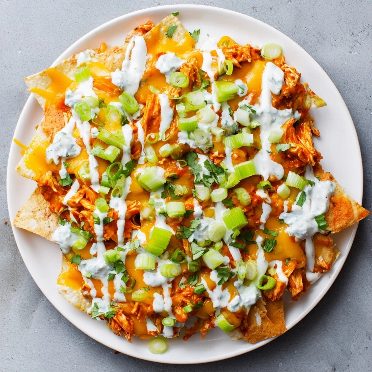 Sizzling hot Buffalo Chicken Nachos fresh from the oven, featuring crispy tortilla chips, spicy buffalo chicken, and a generous drizzle of ranch dressing on top.