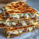 Sizzling griddled Cheesy Griddled Smashburger Quesadillas topped with sweet onions and a drizzle of mayo-mustard sauce.