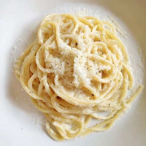 Steaming bowl of Lazy Girl Three-Ingredient Pasta, coated in creamy Parmesan and butter sauce.
