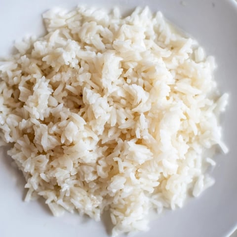 Steaming bowl of Coconut Jasmine Rice, fluffy and fragrant, ready to serve with a Thai curry.