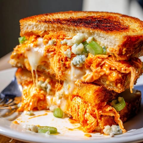 Melty Buffalo Chicken Grilled Cheese sandwich: crispy sourdough exterior, spicy chicken filling.