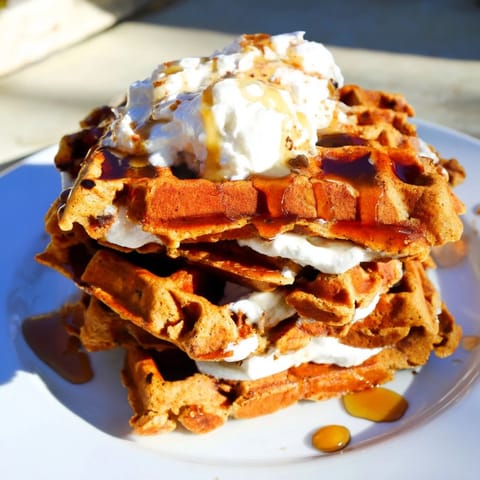 Golden-brown Express Gingerbread Waffle Stacks with whipped cream, ready to serve as a festive breakfast.