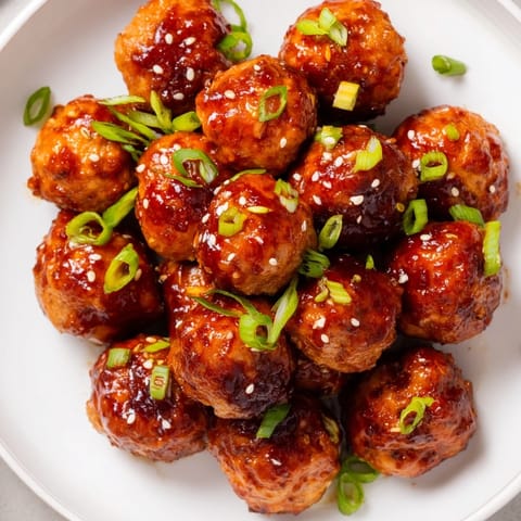 Close-up of vibrant Spicy Honey-Glazed Chicken Meatballs glistening on a platter, ready to be enjoyed.