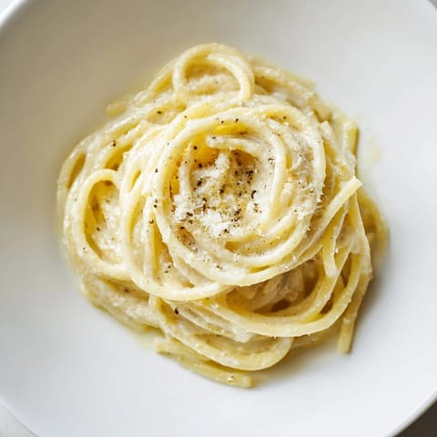 Golden, savory Lazy Girl Three-Ingredient Pasta, ready to serve with extra Parmesan cheese sprinkled on top.