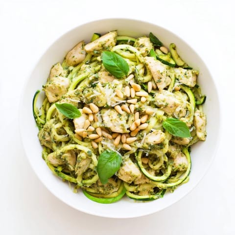 Serving suggestion for Pesto Zucchini Chicken Bowl with toasted pine nuts and grated Parmesan over bright green zucchini noodles.  
