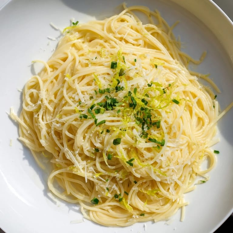 Bright and flavorful Lemon Capellini recipe, with glossy noodles and chopped fresh herbs scattered over the pasta.
