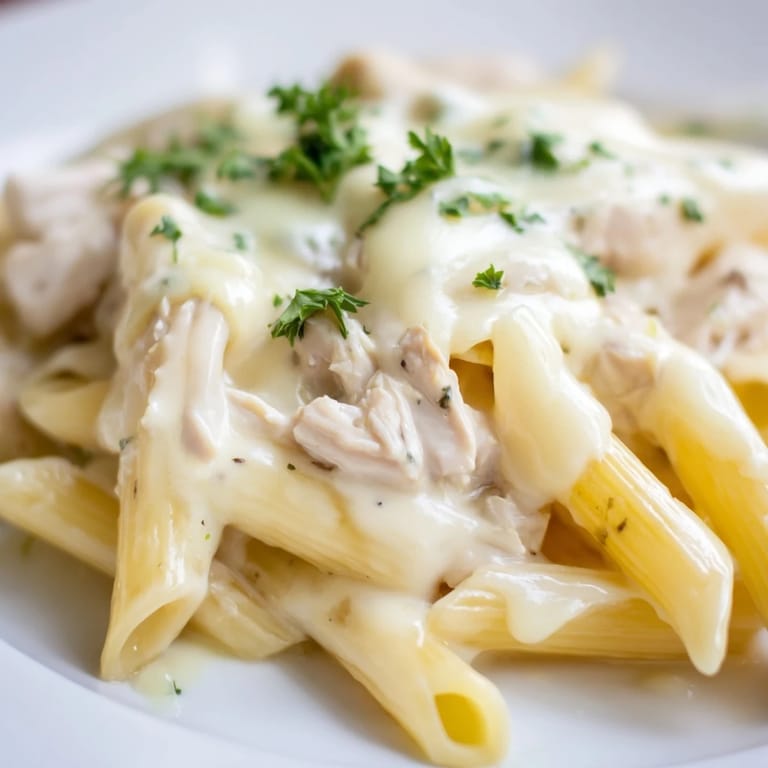 Creamy Chicken Alfredo Casserole with tender chicken, garlic pasta, and golden cheese topping, fresh from the oven in a baking dish.