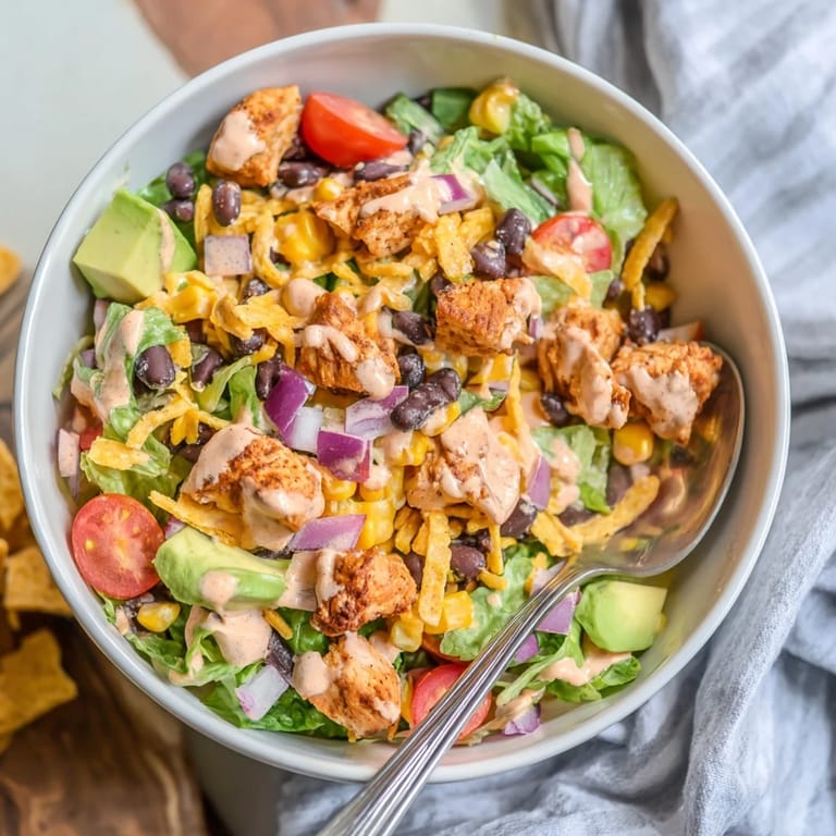 A close-up of Chicken Taco Chopped Salad featuring juicy taco chicken, black beans, corn, cheese, and fresh veggies tossed in zesty salsa ranch.